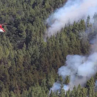 Um helicóptero descarrega água sobre uma zona florestal em chamas em Artenara, na Gran Canaria. FOTO EPA/ELVIRA URQUIJO A.