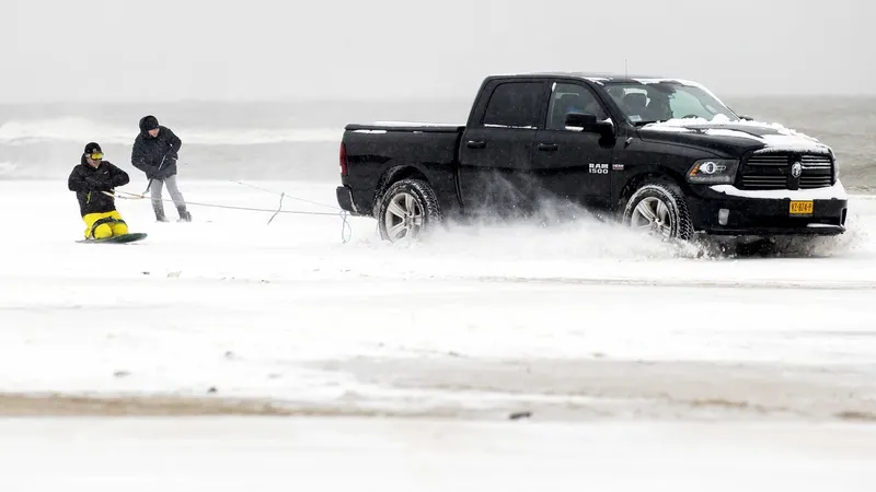 Dois jovens fazem ‘snowboard’ à boleia de uma carrinha em Egmond aan Zee, Holanda. FOTO KOEN VAN WEEL/EPA