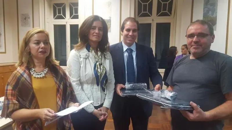 À esquerda, um dos contemplados com a entrega de um computador portátil para o filho